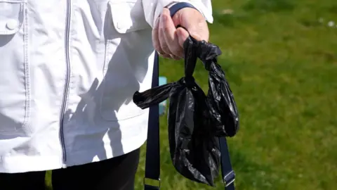 BBC Una foto de cerca de una bolsa de perros negros tenía una persona con una bata blanca. 