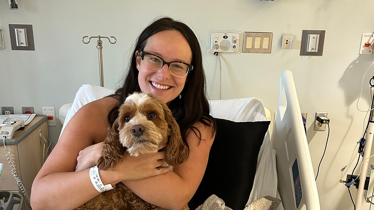 Breanna Bortner sostiene su Cockapoo, Mochi, en el hospital.